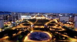 Vista aérea de Brasília à noite, com destaque para o Eixo Monumental iluminado e as avenidas ao redor. Um exemplo de grande área pública que demanda soluções de segurança avançadas e confiáveis, como as fornecidas pela Ôguen.